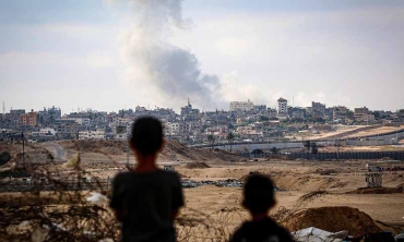 Boys watch smoke billowing during Israeli strikes east of Rafah in the southern Gaza Strip on 13 May 2024 (AFP)